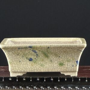 Cracked ceramic pot with blue-green spots.