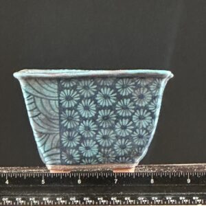 Blue floral ceramic pot with ruler measurement.
