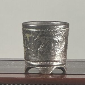Ornate silver cup on display stand.