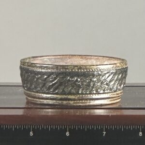 Intricately designed metal band on display stand.