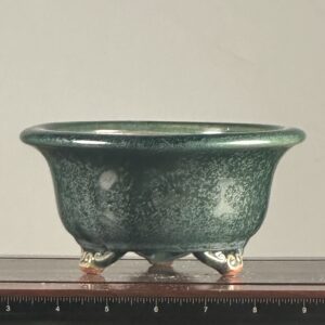 Green ceramic bowl with decorative feet.