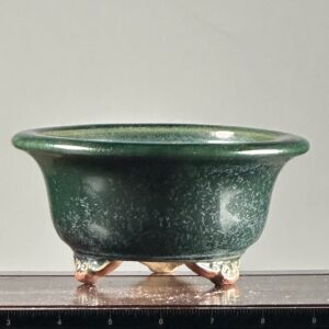 Green ceramic bowl with ornate legs.