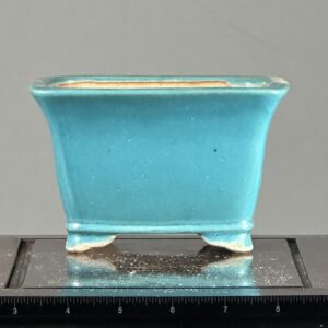 Small turquoise ceramic pot with ruler.